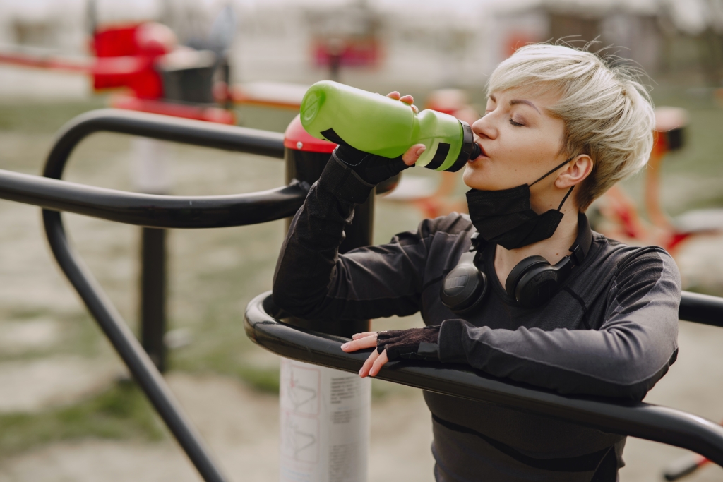緑のボトルでドリンクを飲む女性